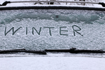 The word WINTER is written on the windshield of a car. First snow.