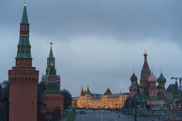Obraz premium Brightly illuminated Red Square, facades of the GUM (Central Department store), Saint Basil's Cathedral, Spasskaya tower of Kremlin and walking people.