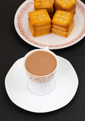 Indian Masala Chai or Morning Tea Served With Biscuits on Black Background
