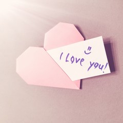 Pink paper heart with the note "I Love You."Valentine's card.
