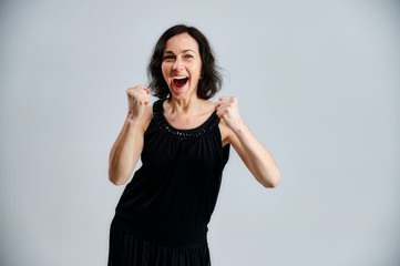 Portrait of a pretty brunette woman in a black dress on a white background. Shows emotions with hands in different poses right in front of the camera.