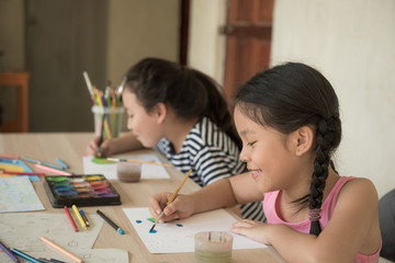 group little girl with brush painting on table in School, education, cut girl painting in at her home. Selective focus and small depth of field, Painting with watercolor, drawing, Creativity concept.