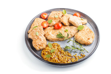 Fried pork chops with tomatoes and herbs on a gray ceramic plate isolated on white background. side view.