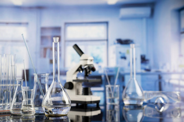 Modern scientific laboratory interior. Laboratory glassware and microscope on the glass table.