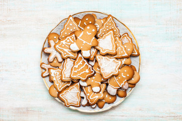 Plate Christmas gingerbread cookies with icing on a white wooden table. Holiday homemade cookies.  Top view. Flat lay