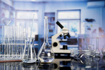 Modern scientific laboratory interior. Laboratory glassware and microscope on the glass table.