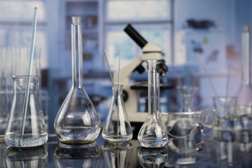 Modern scientific laboratory interior. Laboratory glassware and microscope on the glass table.