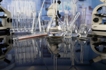 Modern scientific laboratory interior. Laboratory glassware and microscope on the glass table.