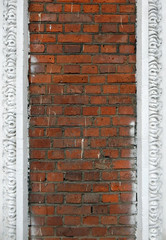 old red brick wall with traces of white paint with white carved elements
