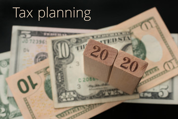 Tax planning concept for business, finance, banking, budgeting, economic topics. Glasses, number 2020, Tax planning text, dollar banknotes background. Selective focus