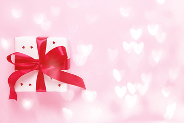 White gift box with hearts on a pink background with bokeh. Valentine's day.
