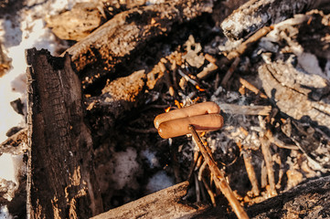 two sausages on a stick fried barbecue on a bonfire in nature