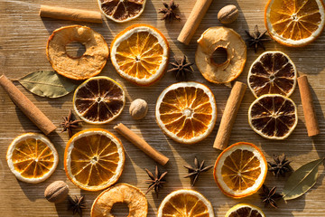 Top view of dry pieces of lemon, orange and apples, cinnamon sticks, bay leaves, nutmegs and star anise as background as ingredients for mulled wine