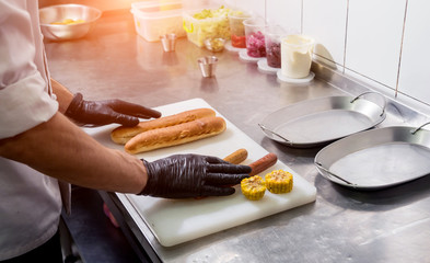 The chef cooking hot dog on a grill. Restaurant.