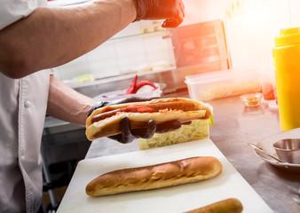 The chef cooking hot dog on a grill. Restaurant.