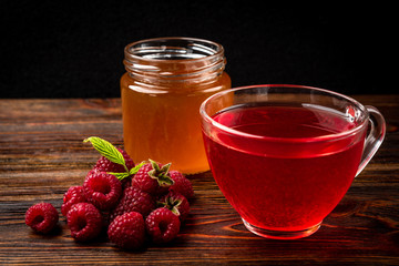 Cup of  tea with raspberry on dark wooden background.