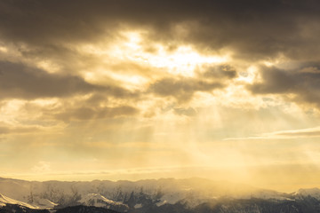 Fototapeta na wymiar Sun rays of light on snow-capped mountain peaks