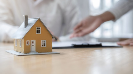 House model with agent and customer discussing for contract to buy, get insurance or loan real...