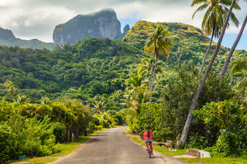 Biking tourist on summer vacation travel discovering by e-bike cycling through forest of Bora Bora...