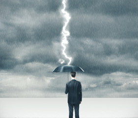 Businessman holding umbrella in storm.