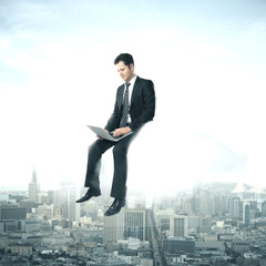 Businessman using laptop sitting on cloud