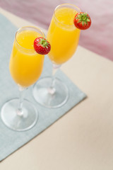 Two glasses of mimosa cocktail (champagne with orange juice) and fresh strawberries