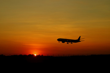 Silhouette of airplane flying on the beautiful sunrise sky