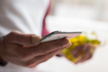 man with mobile phone in one hand and in the other apple and measuring tape, concept of diet and health app