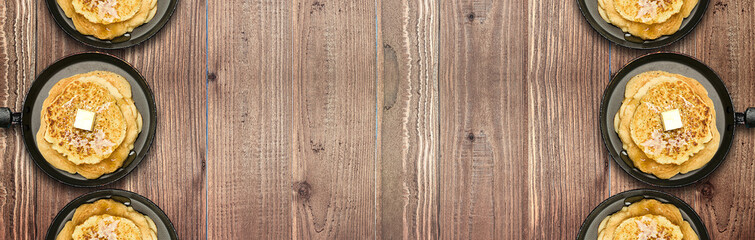 Frying pans with hot delicious pancakes on natural wooden table. Pancake week. Panoramic banner.