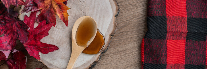 Maple syrup sweet ingredient for desssert recipes, liquid dripping from wooden spoon on wood log...