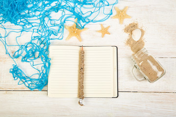 Notebook, starfishes and seashells, glass with sand on white background top view. Planning summer holidays, trip, travel and vacation concept. Flat lay style.