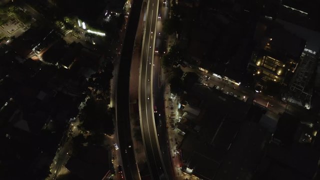 Top Down - night aerial view of Jakarta city after sunset, tall buildings with busy highway with cars passing by. Dolly motion