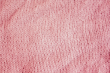 part of the fabric knitted on knitting needles. close-up of a knit fabric loop. coral background