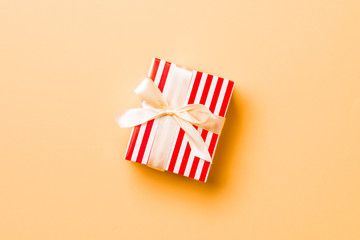 Fototapeta premium Top view Christmas present box with yellow bow on orange background with copy space