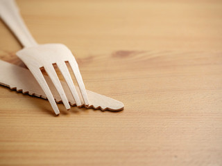 Wooden degradable fork and knife on a light wood table surface, Concept ecology and recyckly issue.