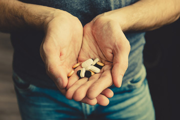 Many of multi-colored pills in male hands.