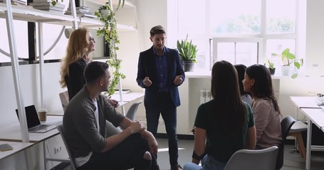 Confident male leader speaking to diverse friendly team in office