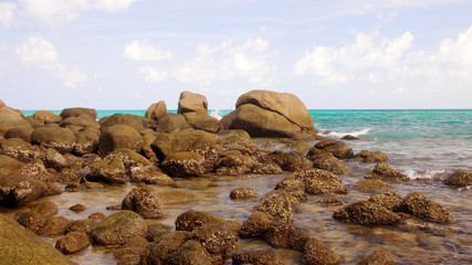 Tropical beach, boulders on the beach, cloudy blue sky, Karon beach, Phuket, Thailand