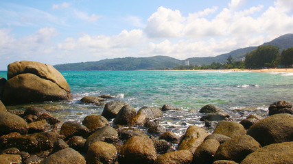 Fototapeta na wymiar Tropical beach, boulders on the beach, cloudy blue sky, Karon beach, Phuket, Thailand