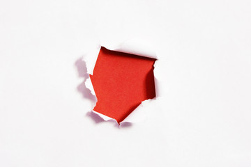 Torn hole and ripped of paper on red background