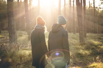 Foto op Aluminium Couple in warm clothing taking a walk inside a sunny forest © photoschmidt