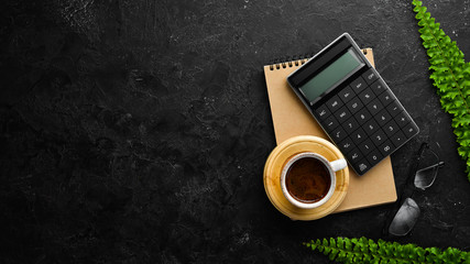 Calculator and office tools on a stone black desk. Top view. Free space for your text.