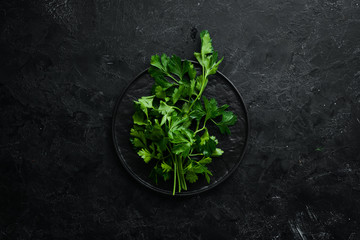 Fresh green parsley on black stone background. Vegetables. Top view. Free space for your text.