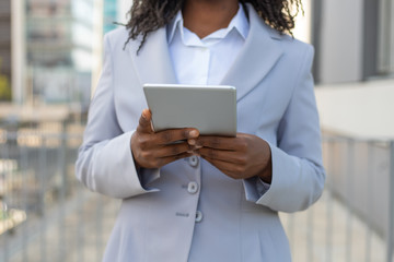 Closeup of tablet in African American woman hands. Business woman with digital device going down city street. Communication concept