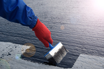 Worker applies bitumen mastic on the foundation