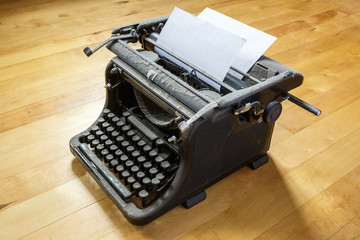 old vintage dust-covered typewriter with sheet of white paper