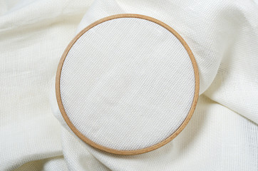 Fototapeta na wymiar Closeup of wooden embroidery hoop and clean white fabric for hobby needlework.Empty space for design. Template for hobby design