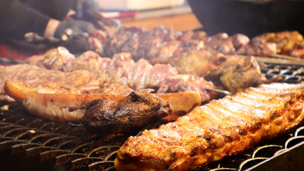 Fried pork ribs. Grilled pork kebabs on a teapot. Barbecue Kid on the grill. grilled kebab, kebab. Festival of delicious fried street food. The meat on the bone, the cooking process