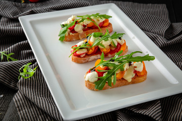 Crispy bruschettas with tomatoes, feta cheese and pesto. Restaurant menu.