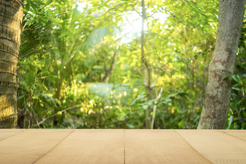 Pine wood table top (Bar) with blur on green palm leaves or tree in tropical forest with bokeh light at background